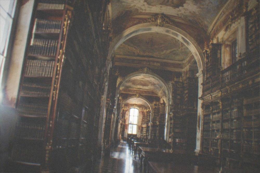 Baroque interior of the Biblioteca Joanina with tall wooden bookshelves and painted ceilings