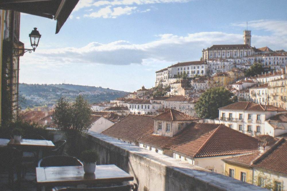 Sunlit terrace overlooking Coimbra's rooftops on a warm clear afternoon