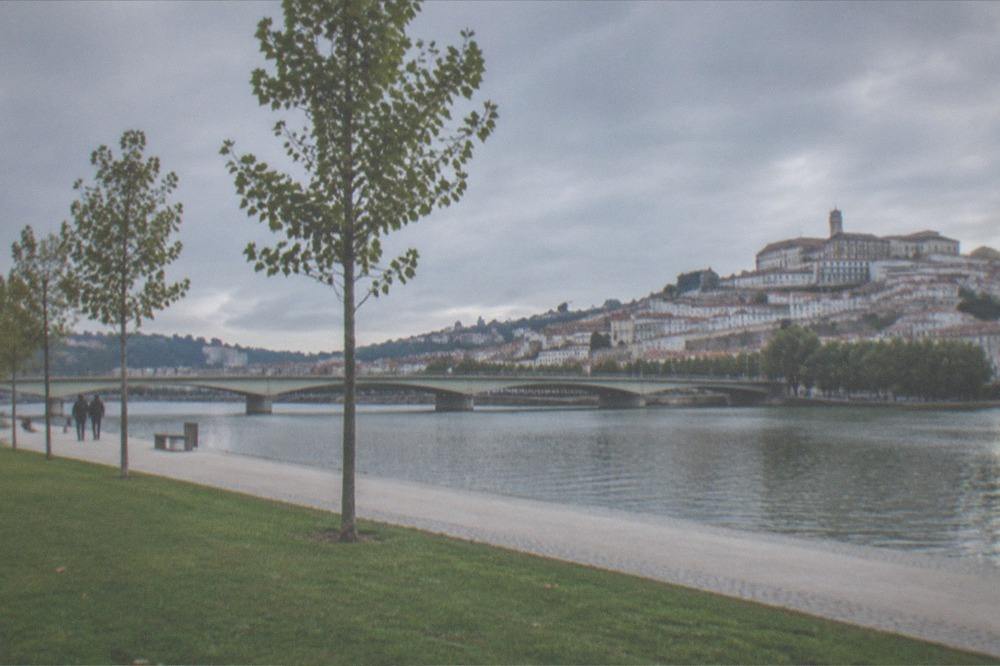 River Mondego flowing past Coimbra's old town with the bridge and hillside buildings