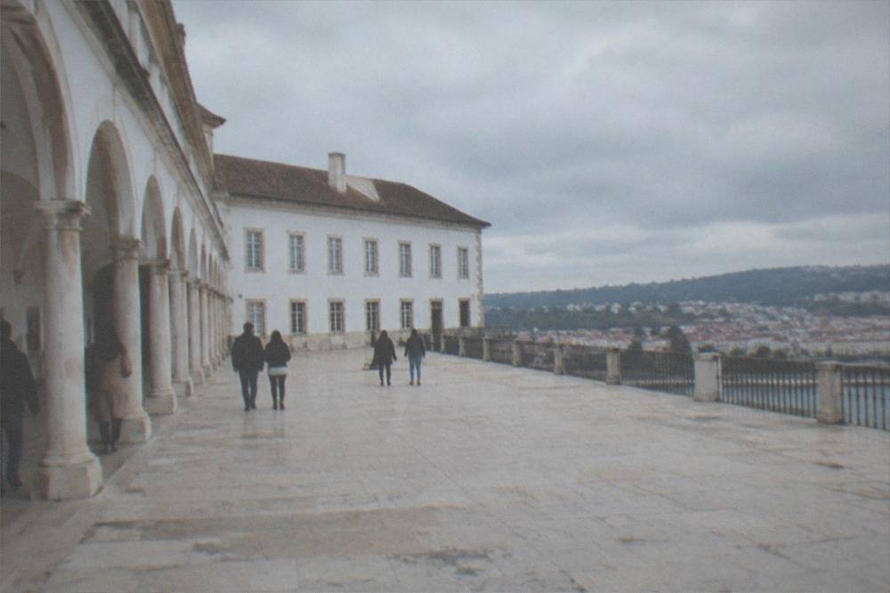 Visitors walking through the arcaded courtyard of the University of Coimbra