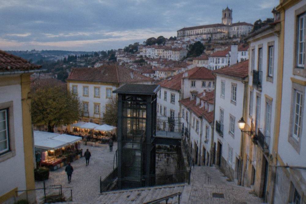 The lower station of a city hill lift with a street market square nearby in Coimbra