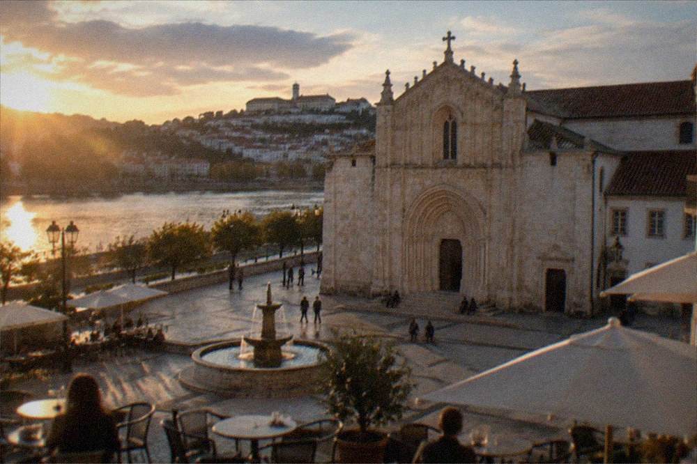 Evening light on a riverside café terrace with the illuminated university hill behind