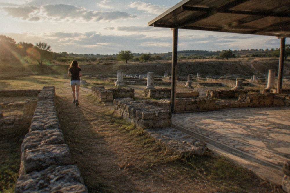 Roman stone walls and column bases of the excavated ruins at Conimbriga under a clear sky
