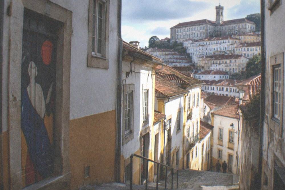 A narrow old town street in Coimbra with a painted student republic door