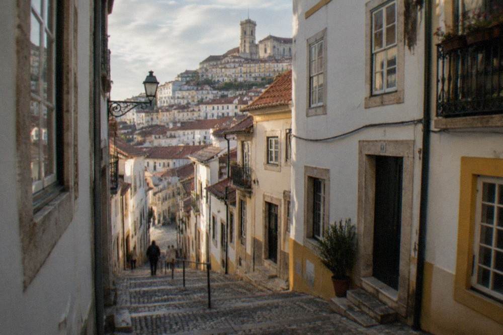 Steep cobbled street in the old town of Coimbra with whitewashed houses