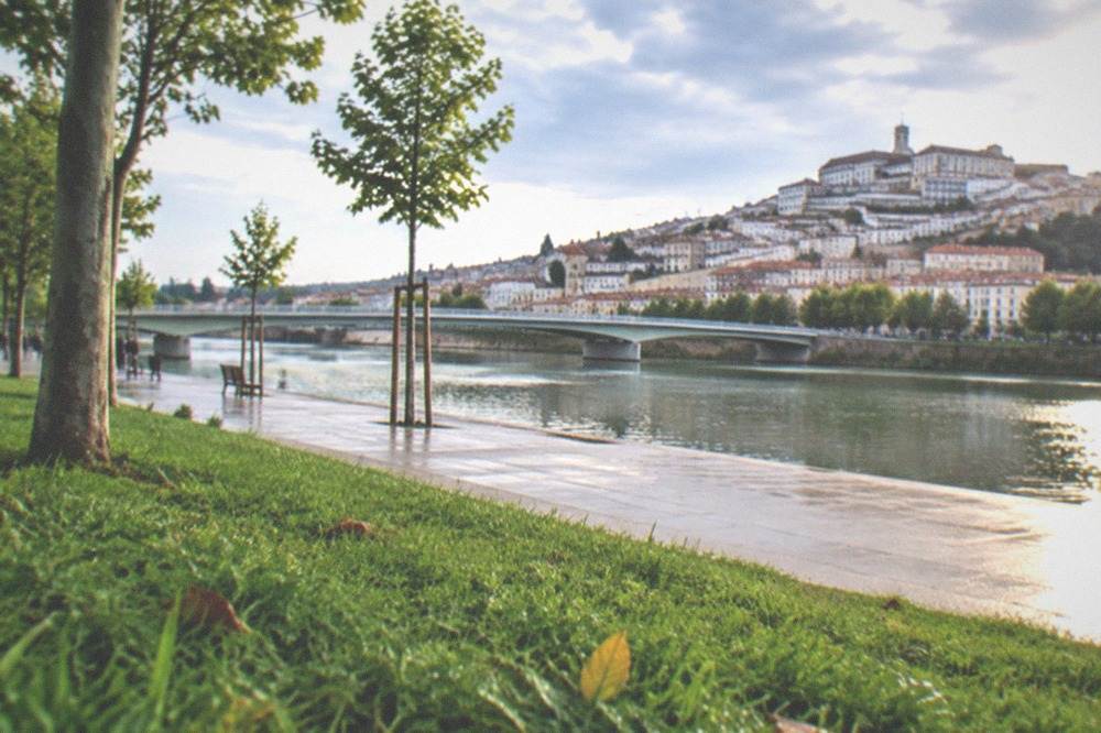 The Mondego riverside park in Coimbra with the old town rising on the far bank