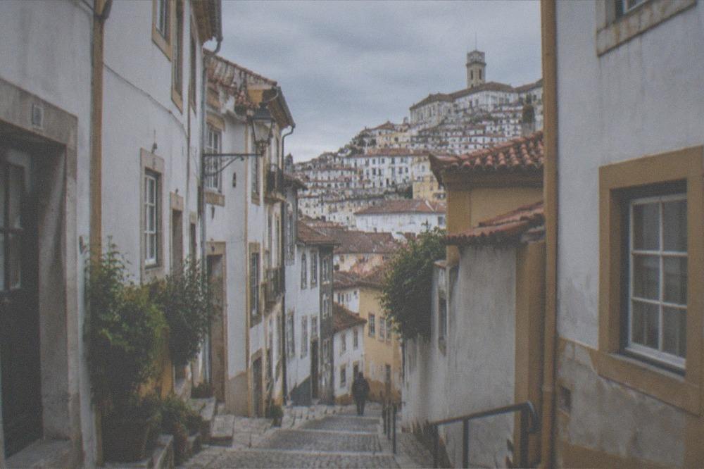 A narrow cobbled lane in the old town of Coimbra with whitewashed and ochre buildings
