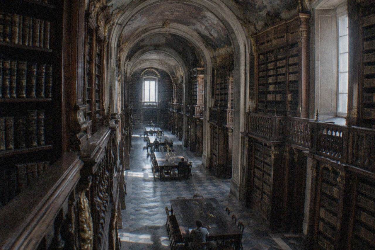 Ornate baroque reading room of the Joanina Library in Coimbra with tall wooden bookshelves and painted ceilings