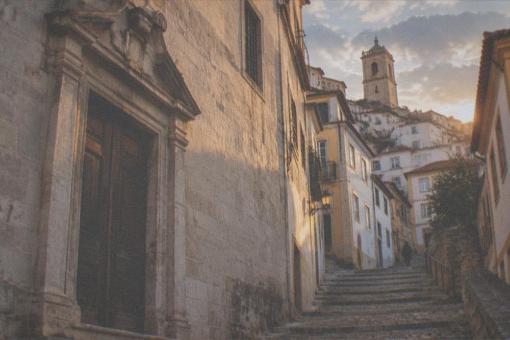 Closed wooden door of a historic university building with stone walls in Coimbra