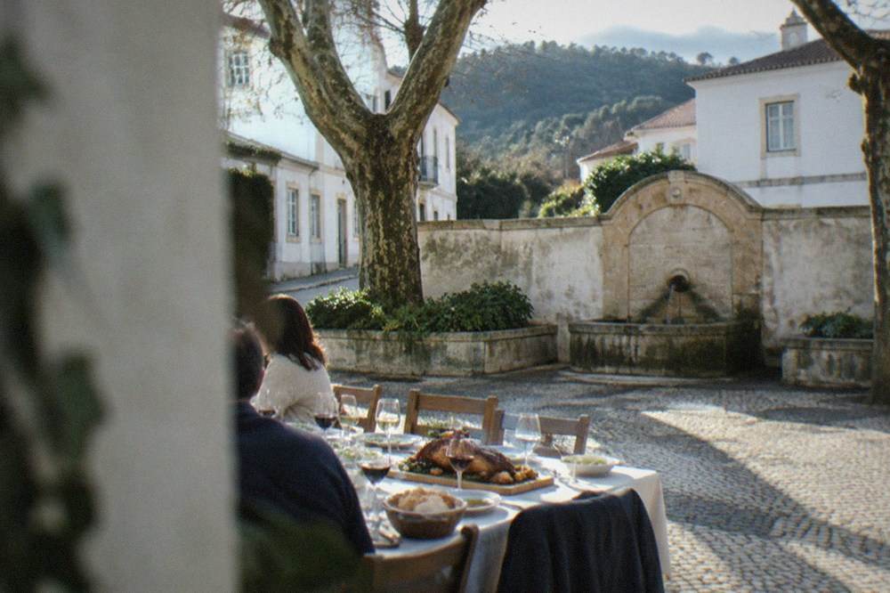 A family table set for a long lunch with wine glasses, bread and a roast pig board