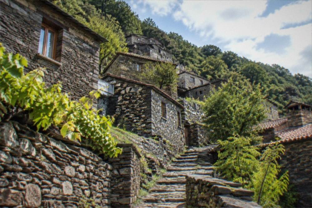 Slate-roofed schist village houses on a green Lousã mountainside