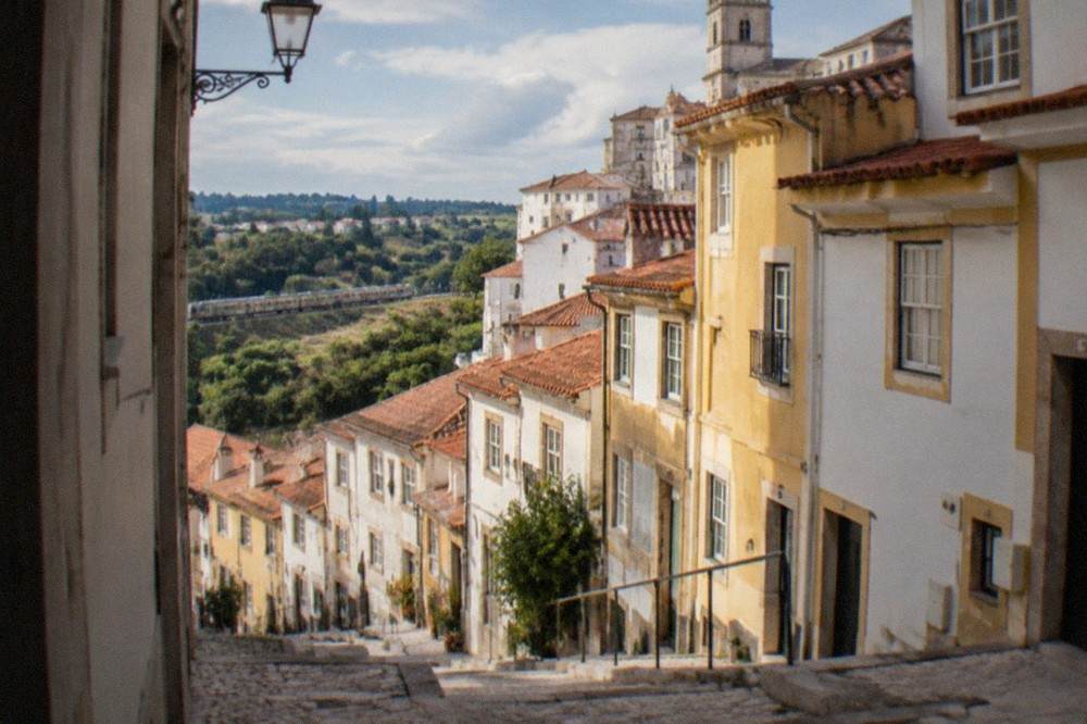 A train travelling through green countryside past small Portuguese towns