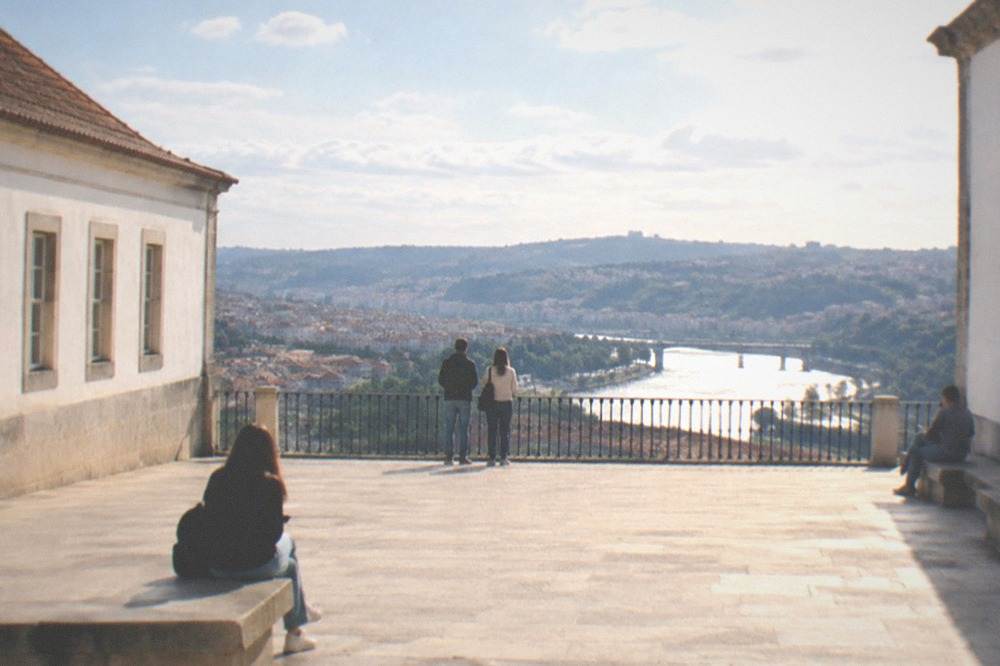 A stone university courtyard with a wide view over a river city skyline
