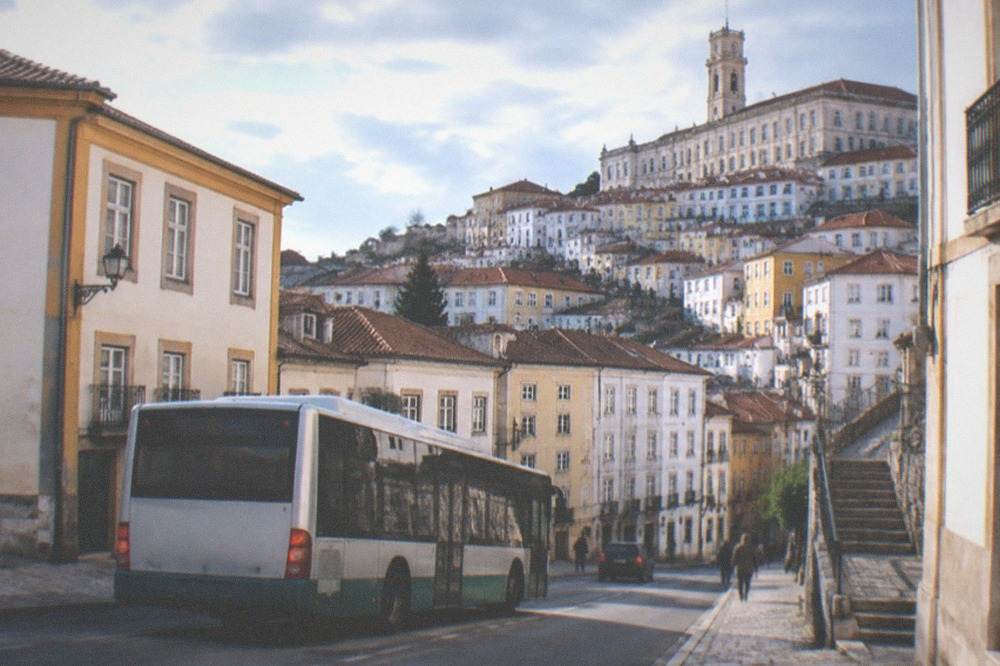City bus on a street in Coimbra with the old town buildings behind it