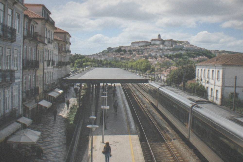 A railway platform in Coimbra with the city hill visible in the distance