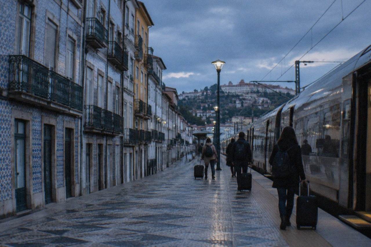 A train waiting on a platform at a Portuguese railway station with travellers holding luggage