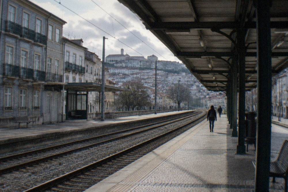 The platform and tracks of a Portuguese railway station seen from under a canopy