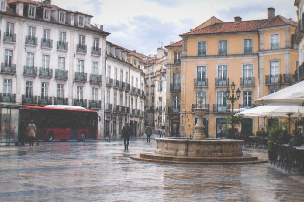 A red city bus stopped at a street stop in a Portuguese city centre