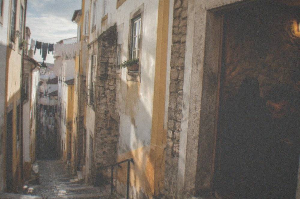 Two singers in black academic capes performing fado in a small stone-walled room in Coimbra