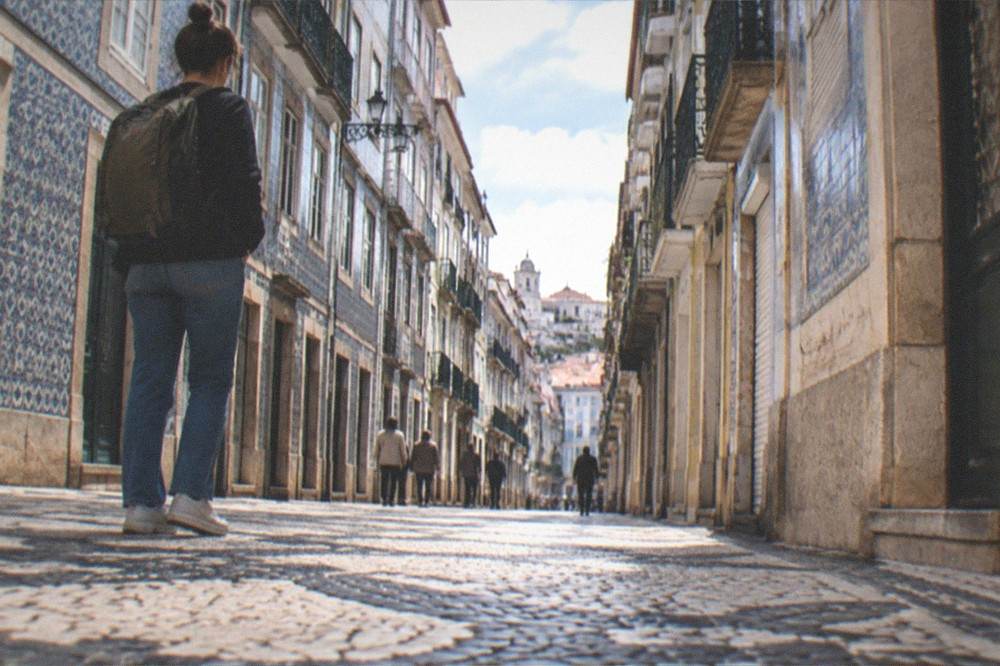 A traveller with a backpack looking at a departure board in a Portuguese railway station