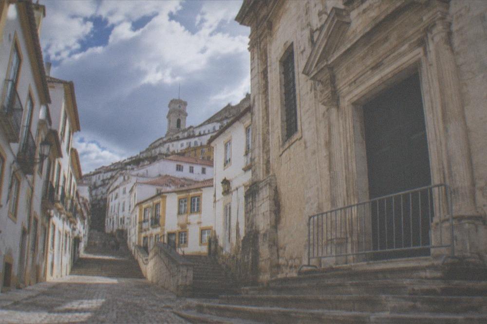 The stone facade of a closed museum building in Coimbra with a barrier across its entrance steps