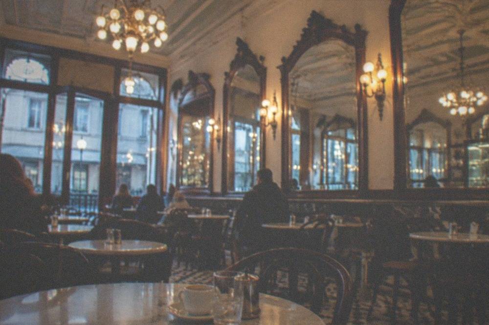 The ornate interior of an old Portuguese café with mirrors, chandeliers and marble-topped tables