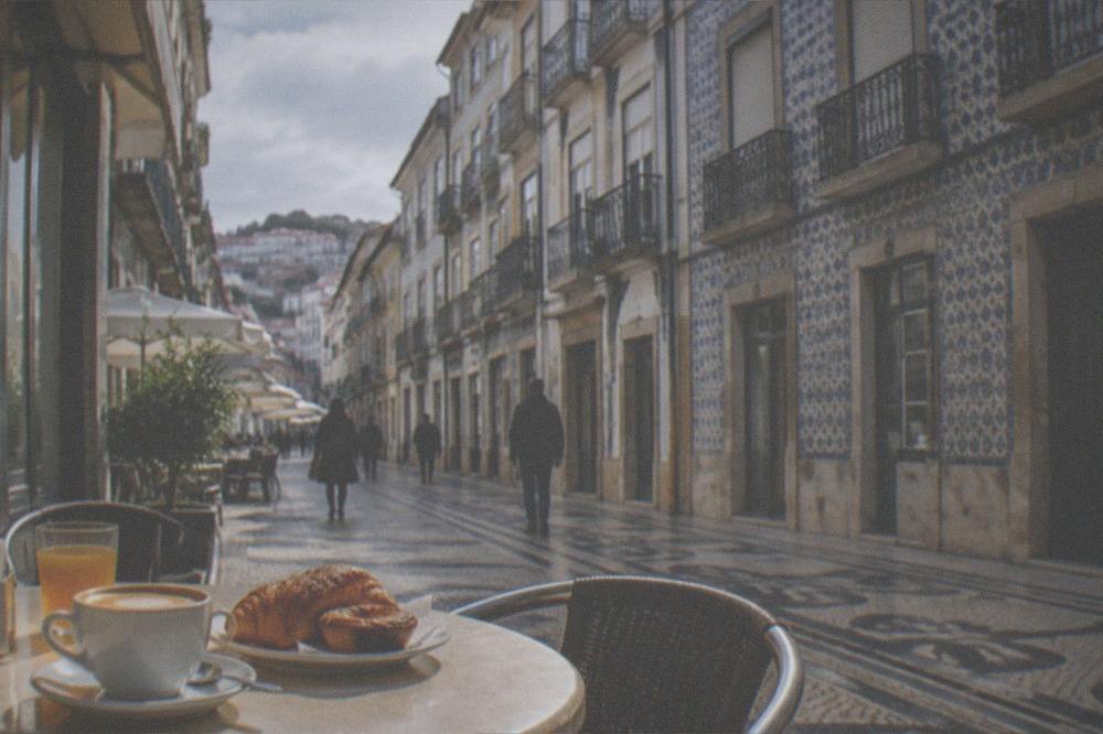 A café terrace table with coffee and pastries in warm morning sunlight