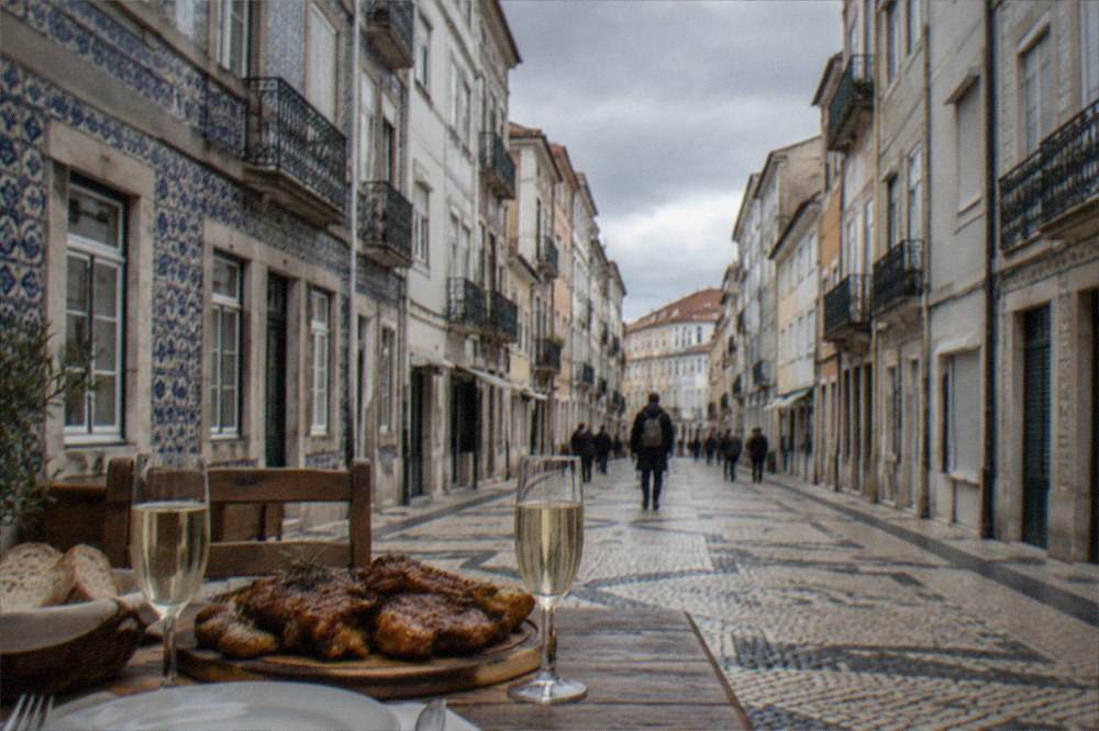 A rustic lunch table with roast meat, bread and glasses of sparkling wine