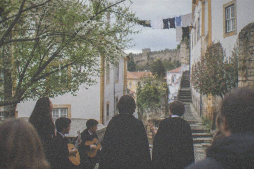 Students singing fado in black capes with guitars in a Coimbra square