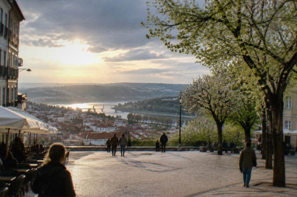 A view over Coimbra's old town rooftops toward the river at dusk