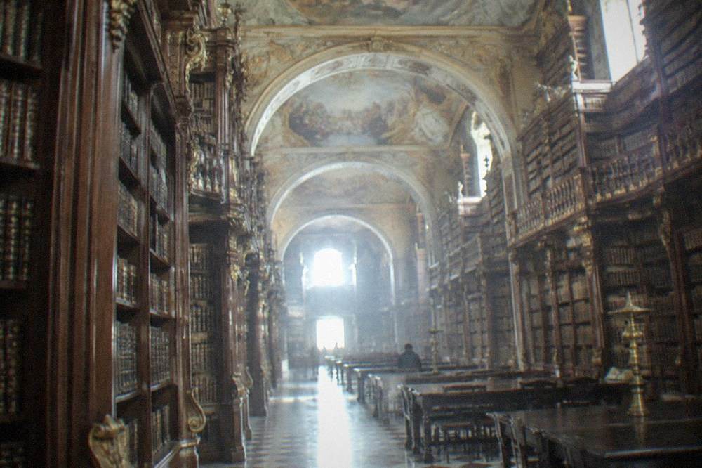The baroque interior of the Joanina Library with tall wooden bookshelves and painted ceilings