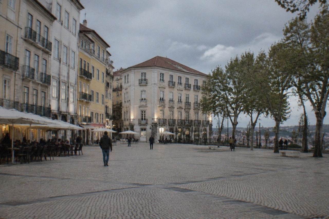 A narrow street in Coimbra's old town with an old building facade lit by evening light