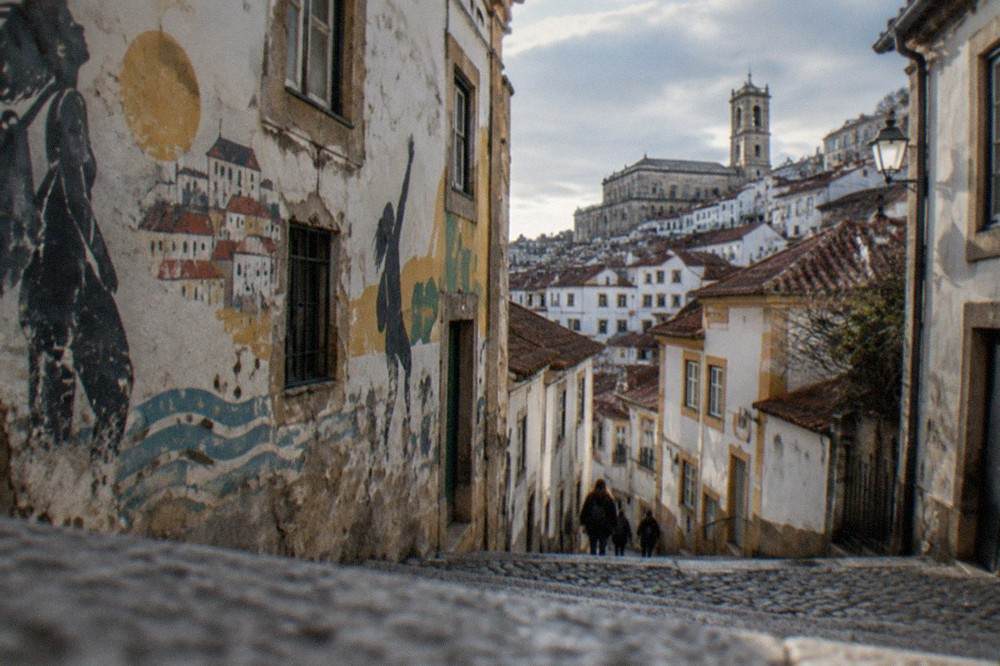 A weathered house facade covered in painted student slogans and banners in Coimbra