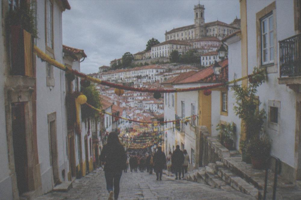A festive street in Coimbra filled with people and decorations during a celebration