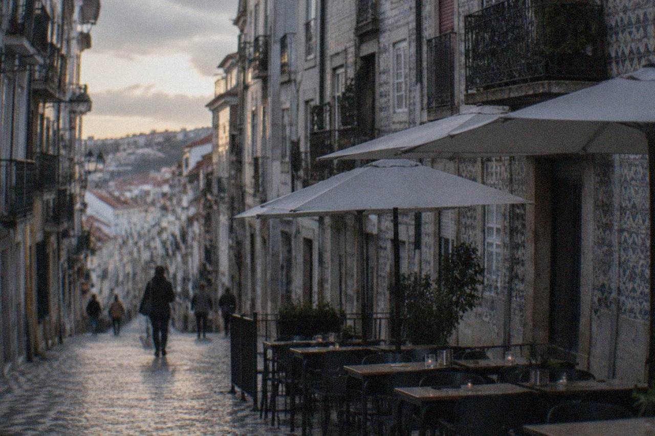 Outdoor tables of a restaurant on a cobbled street in Coimbra's old town at dusk