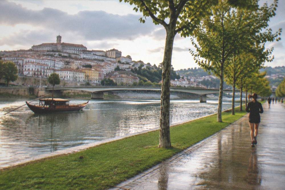 A wooden traditional boat on the River Mondego with Coimbra's old town in the background