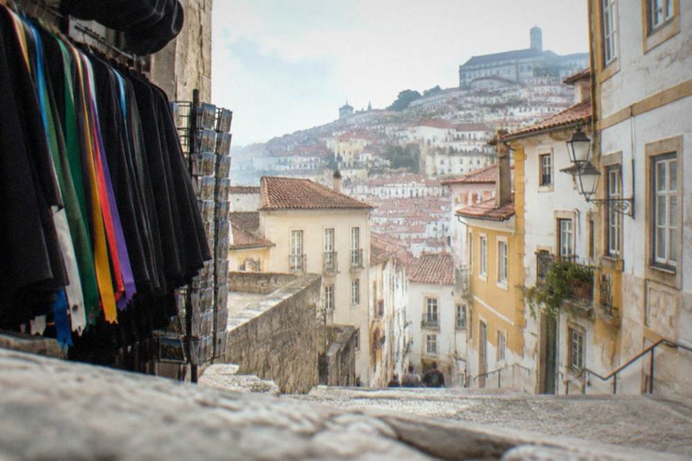 Student capes in black and coloured ribbons hanging in a Coimbra souvenir shop