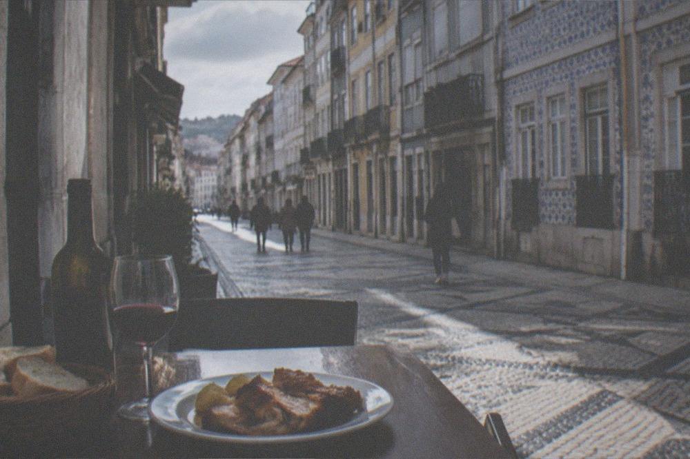 A table with a bottle of regional wine, bread and a plate of roast pork