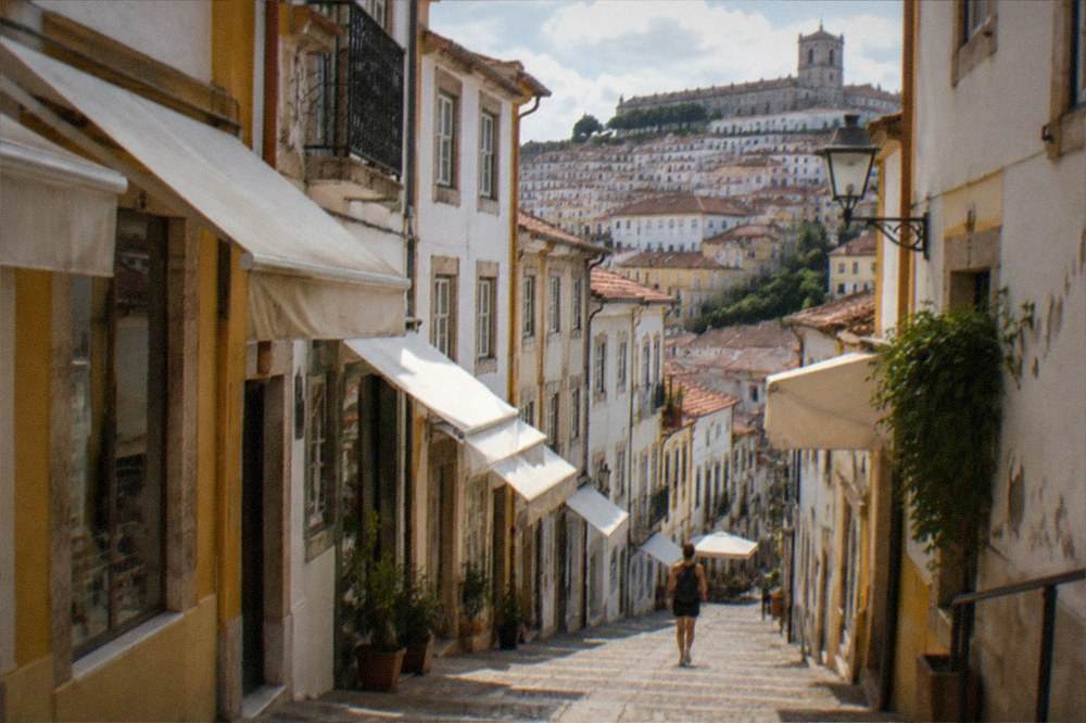 A shaded old street in Coimbra on a warm afternoon with awnings over shopfronts