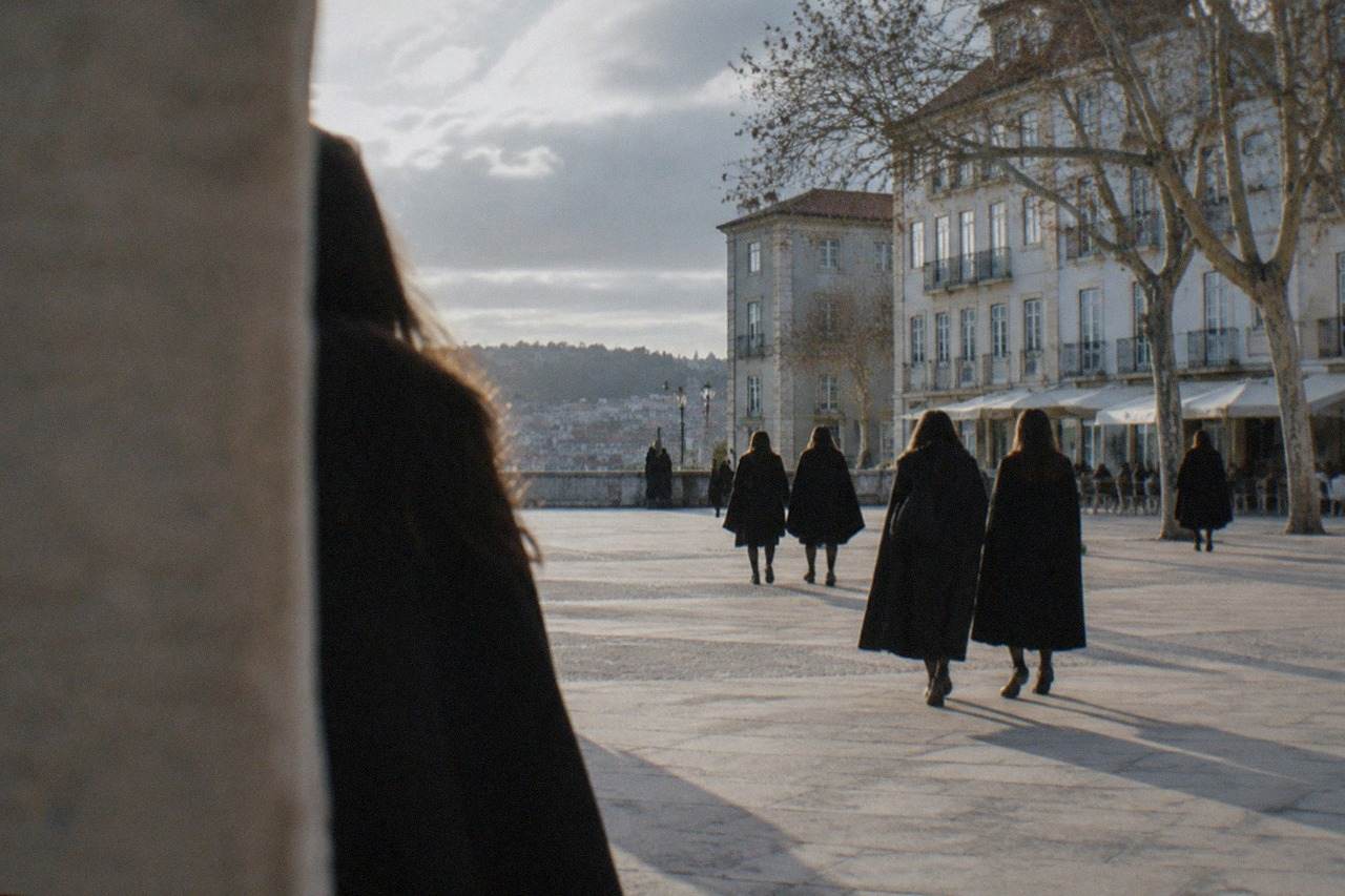 Students in black capes walking through the old university hill in Coimbra, Portugal