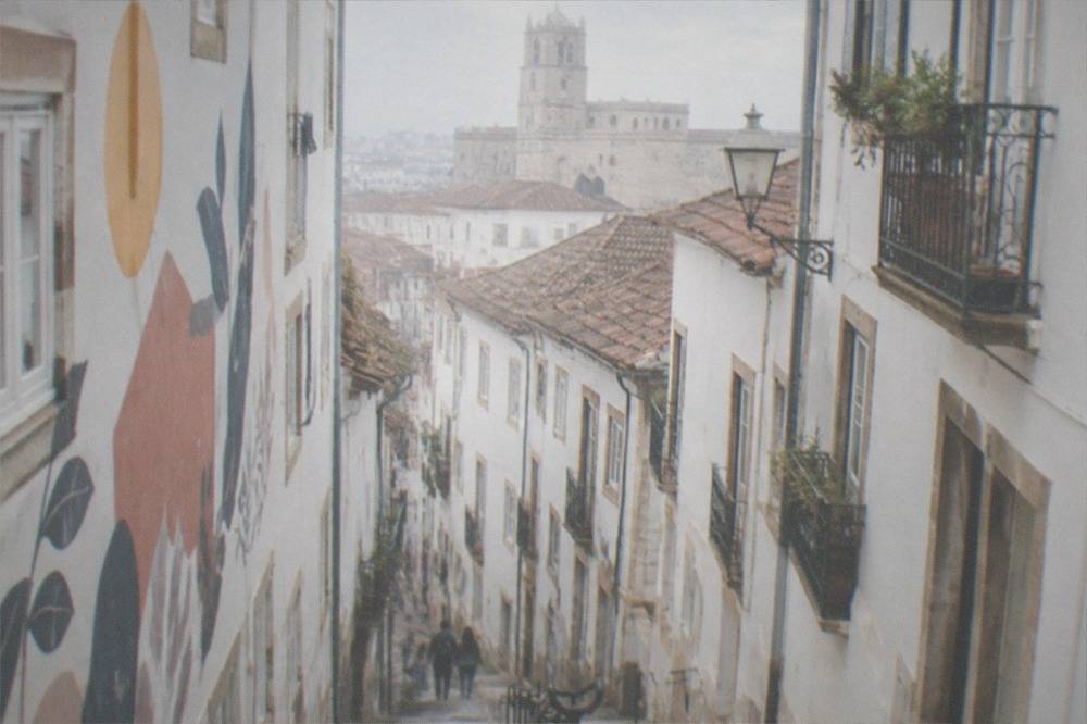 A student house facade covered in painted slogans and murals on a Coimbra street