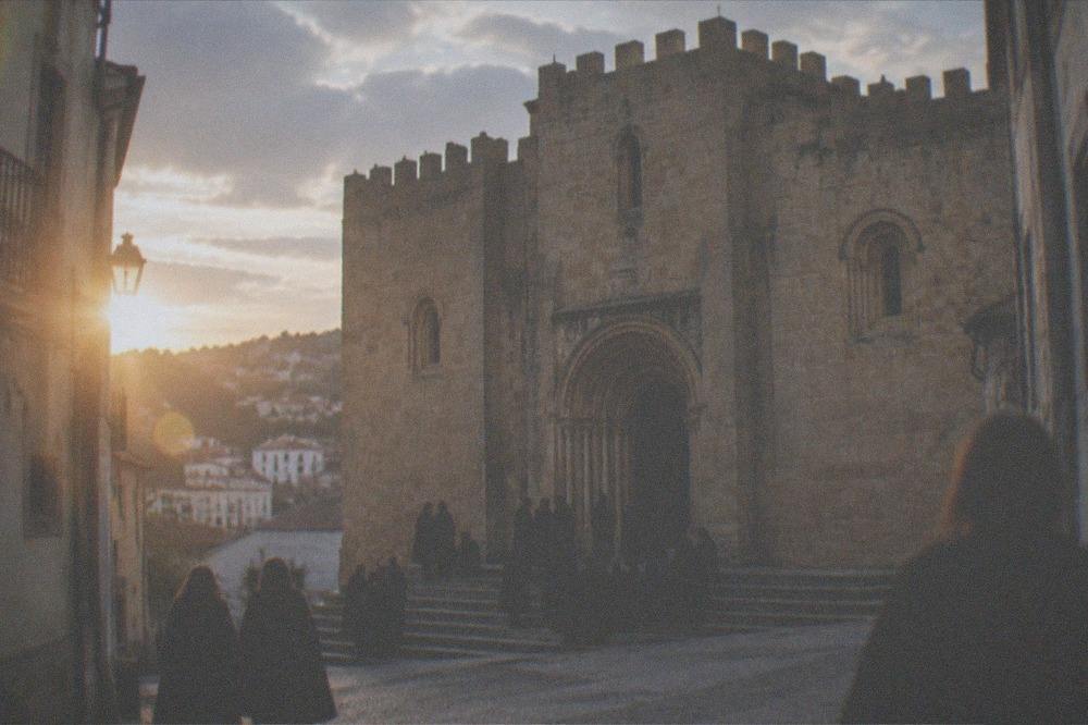 Students in black capes gathered on the steps of the old cathedral in Coimbra at dusk