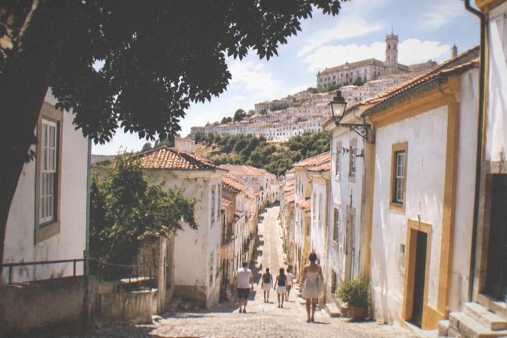 A narrow cobbled street of whitewashed houses climbing toward the university hill in Coimbra