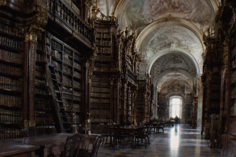 Baroque interior of the Biblioteca Joanina with tall wooden bookshelves and painted ceilings