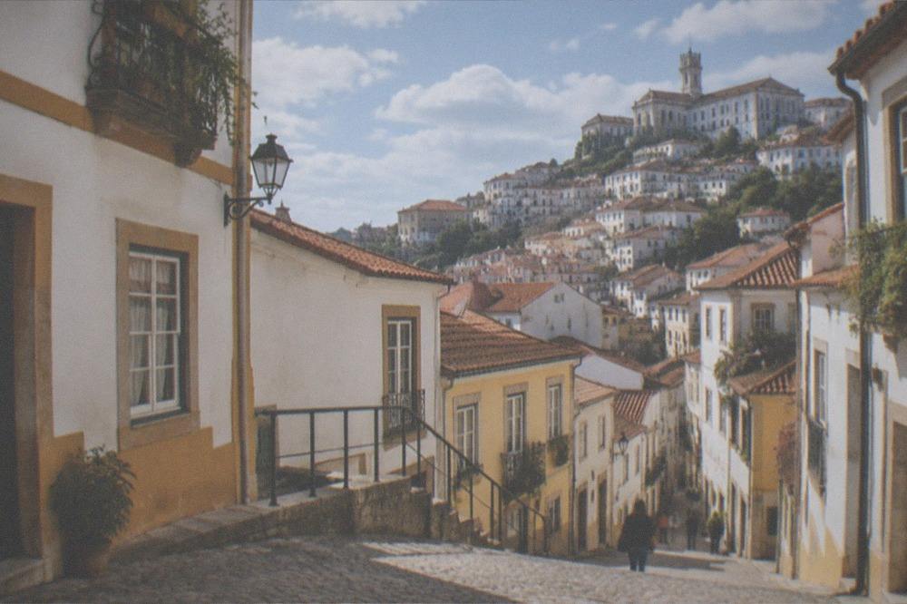 Sunlit cobblestone street in Coimbra's old town on a warm clear day