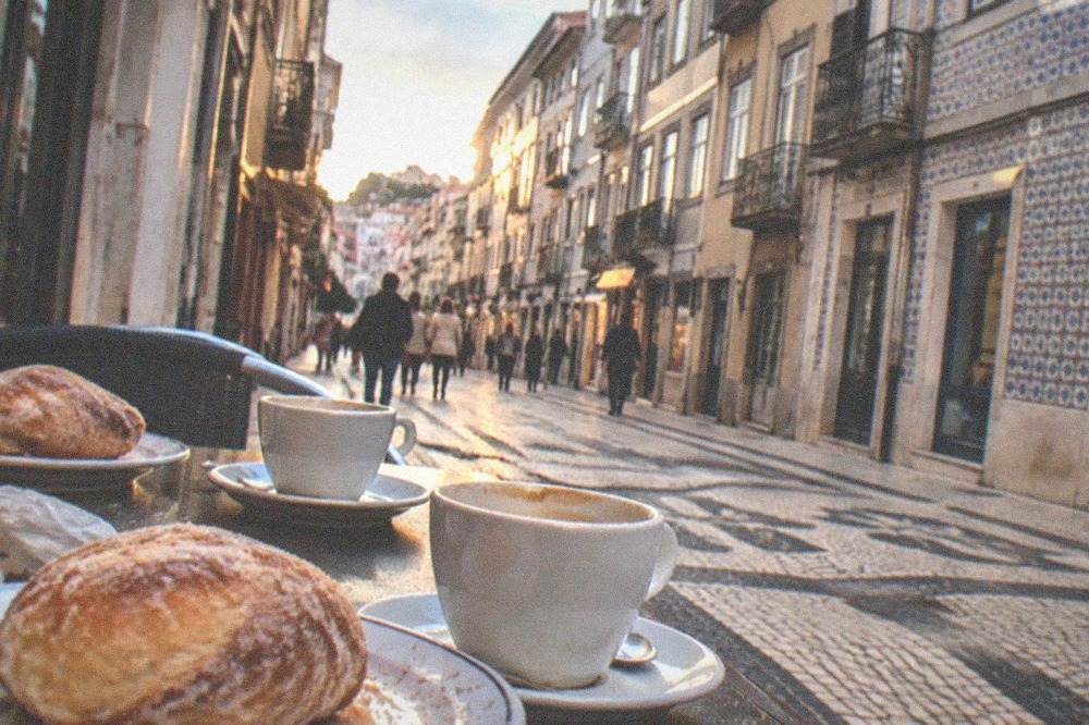 Sugar-crusted arrufada buns on a café counter next to cups of coffee