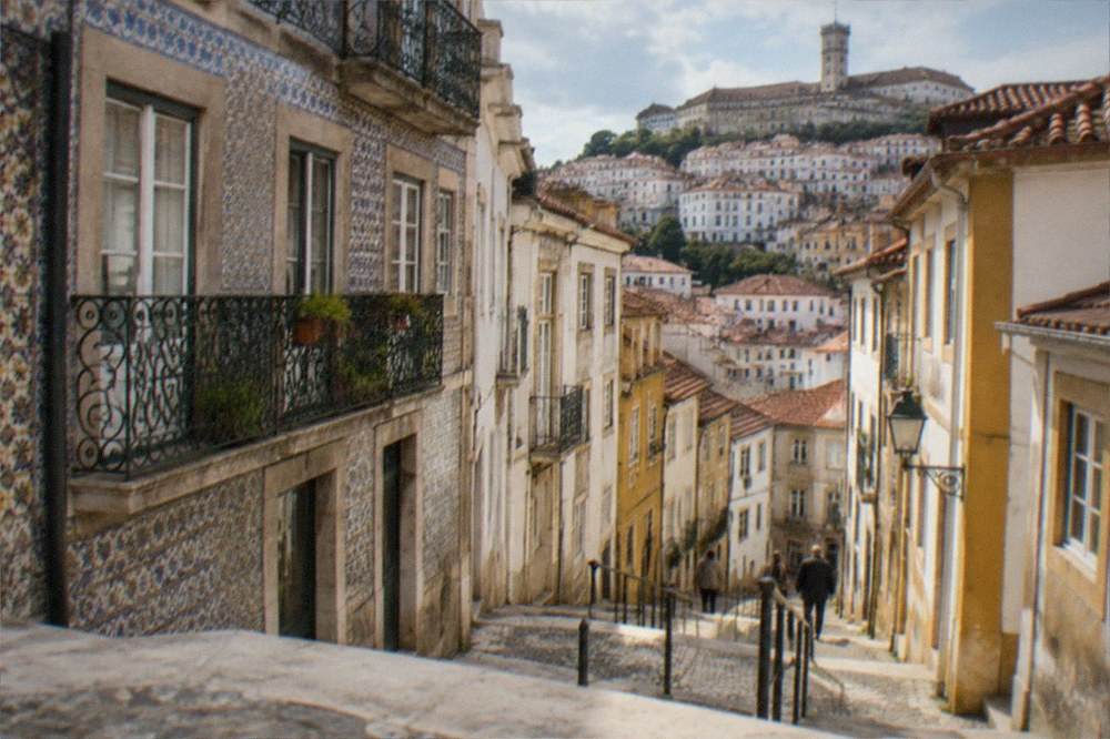 A tiled building facade with wrought-iron balconies on a street in central Coimbra.