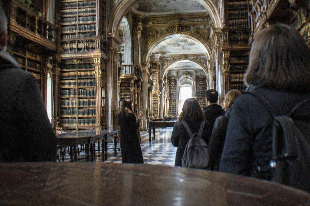 A tour guide speaking to a small group outside the Joanina Library at the University of Coimbra