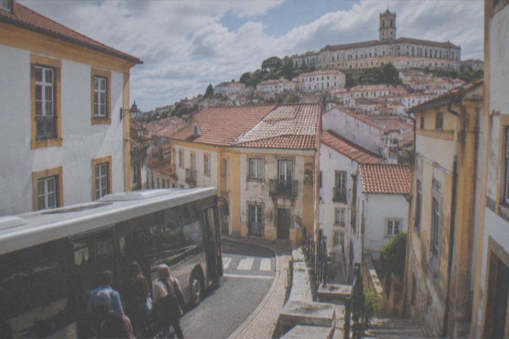 A bus stopped on a Coimbra street with passengers boarding