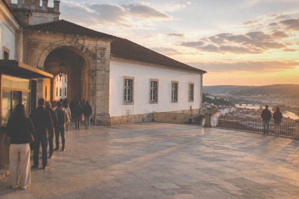 A ticket kiosk and stone archway at the university with visitors queuing in warm light